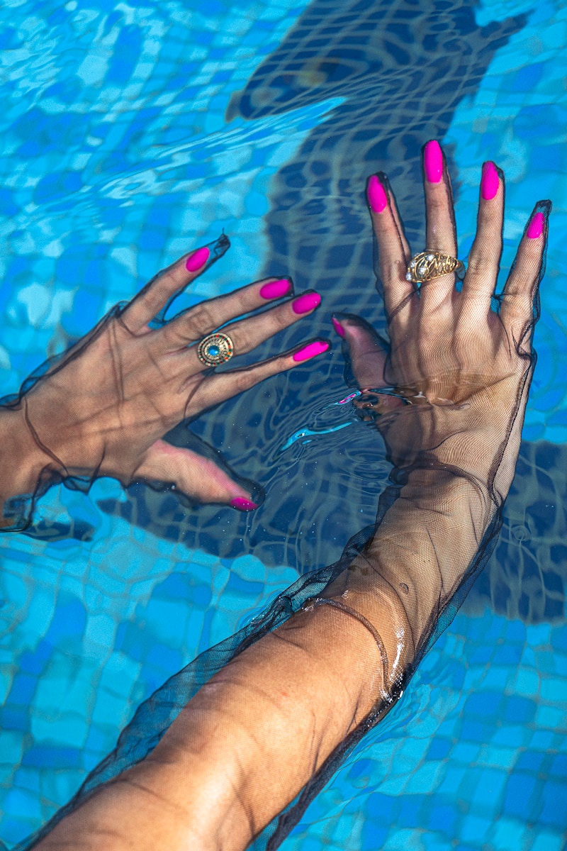 A woman's hand with pink nail polish in a swimming pool
